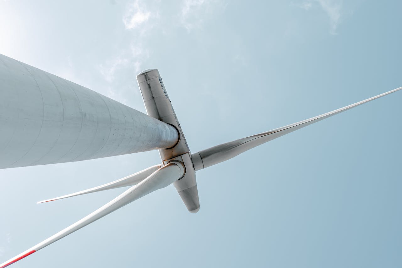 Looking up at a majestic wind turbine under a clear blue sky, showcasing renewable energy innovation.